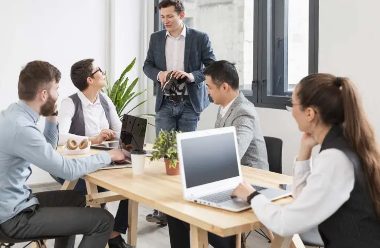 Team members collaborating in a wellness-focused office space with standing desks and natural elements